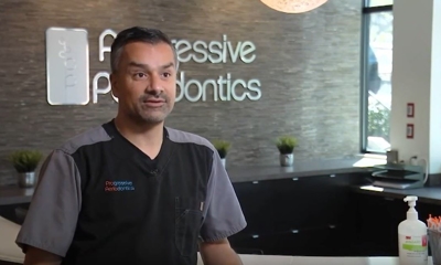Male dental professional in scrubs at Progressive Periodontics office reception area.