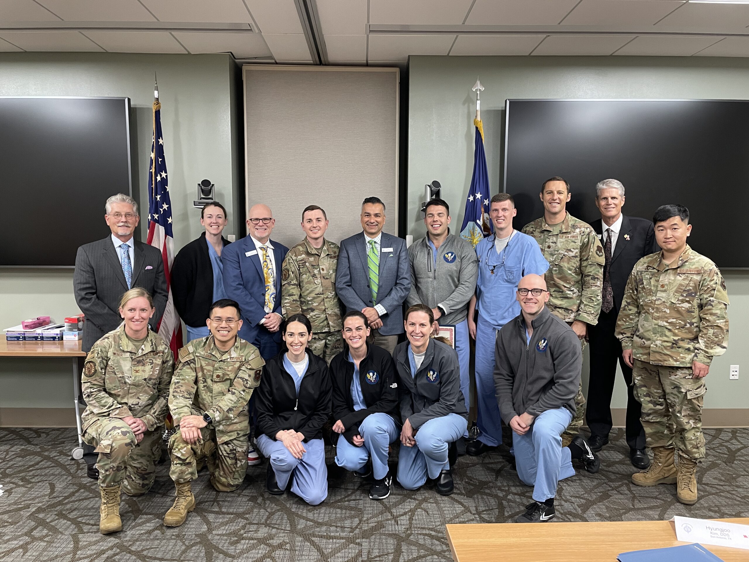 Group photo of military personnel and civilians in classroom setting with blackboard backdrop.