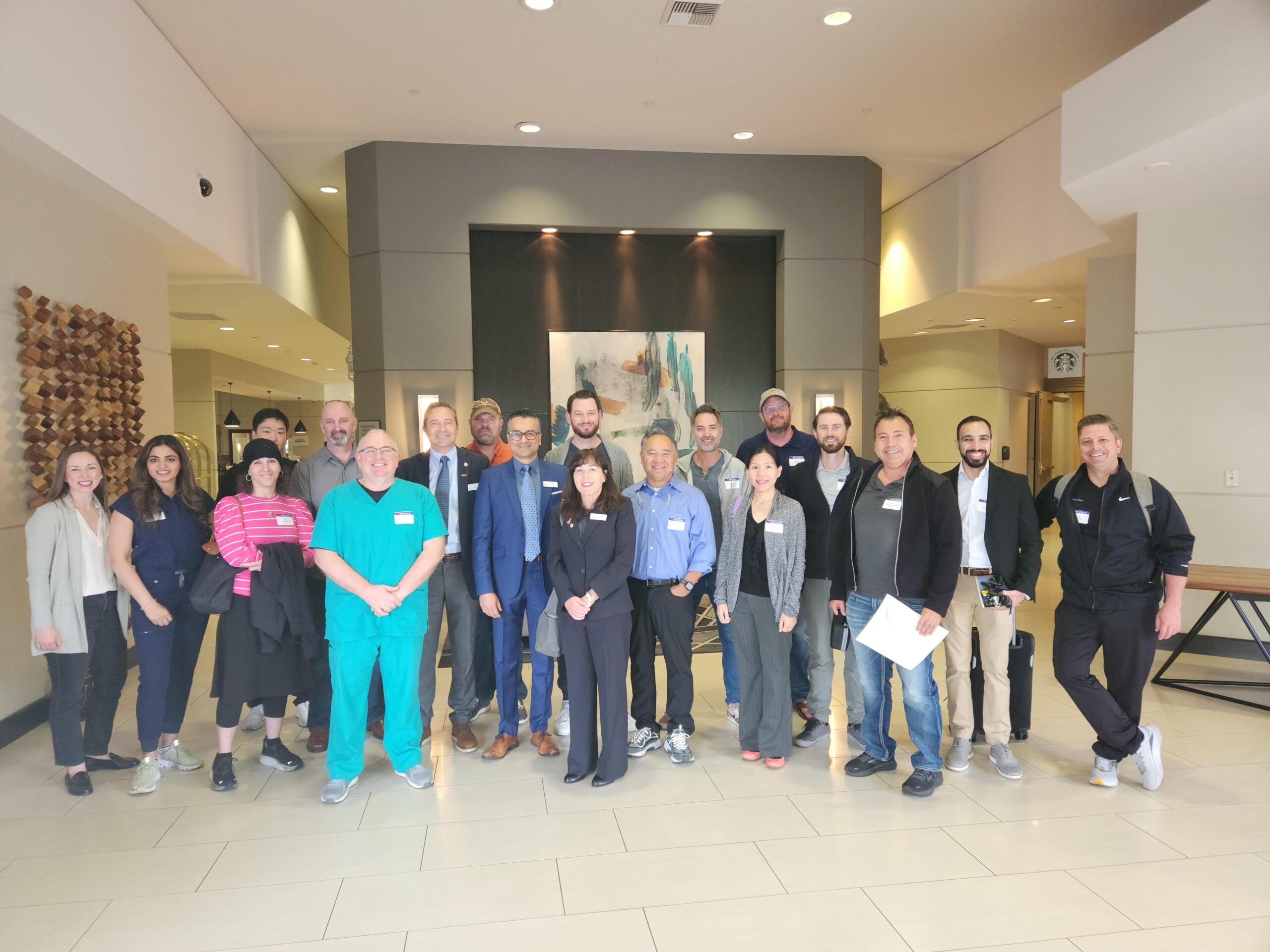 Large group of dental professionals and staff posing together in modern clinic hallway