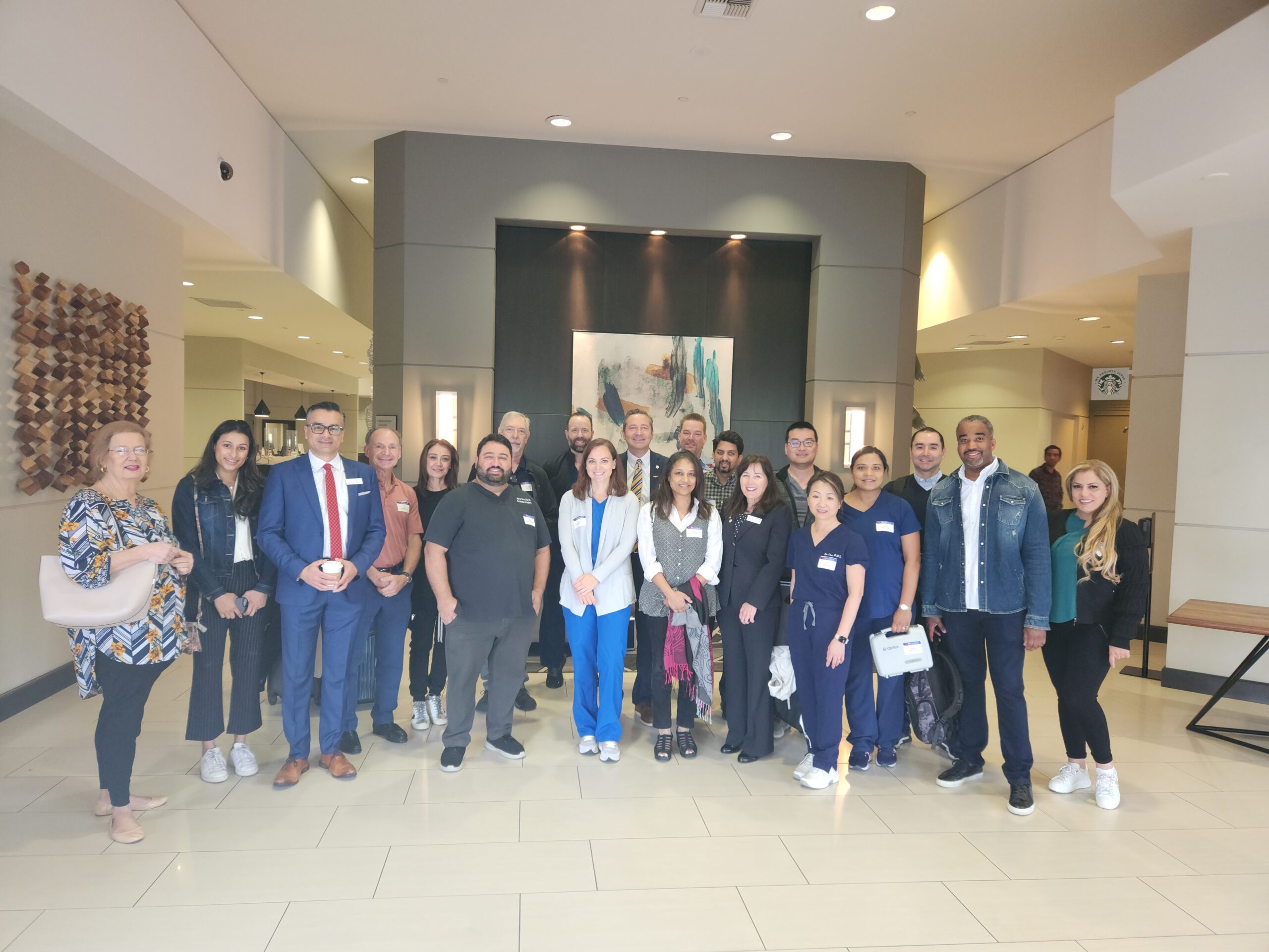 Group of dental professionals posing together in modern clinic hallway for team photo.